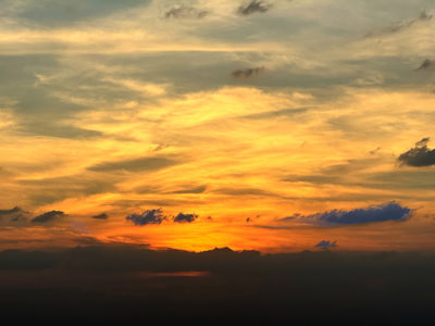 A colorful sunset sky in Dubai, with orange and yellow clouds against a darkening horizon.