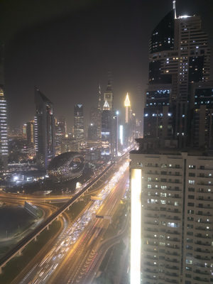 Night view of Sheikh Zayed Road in Dubai with illuminated skyscrapers and moving traffic.