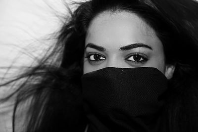 A powerful black-and-white portrait capturing expressive eyes framed by flowing hair and a partially covered face. The high contrast and intimate close-up create a mysterious, emotive image perfect for artistic, fashion, and conceptual photography themes.